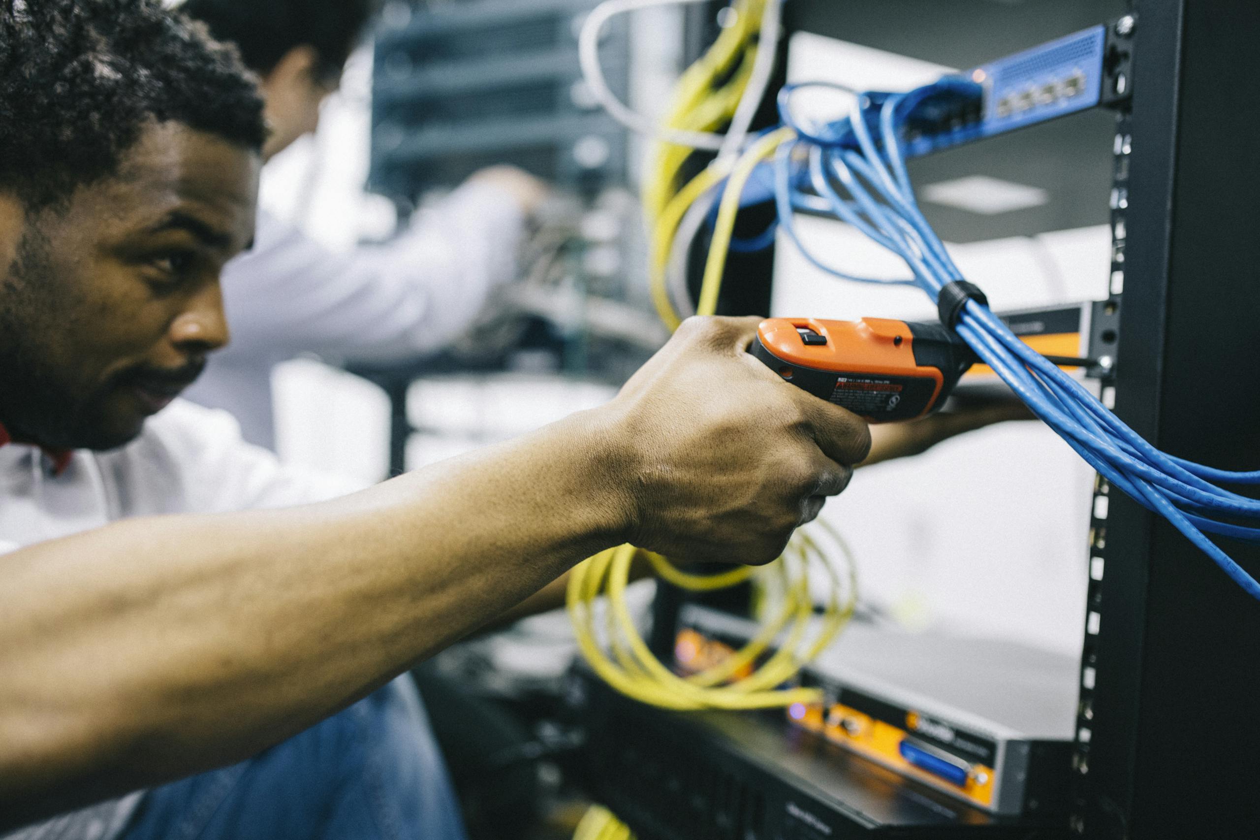An engineer inspects network cables and connections in a server room, focusing with precision.